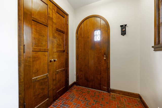 foyer entrance with baseboards and brick patterned floor