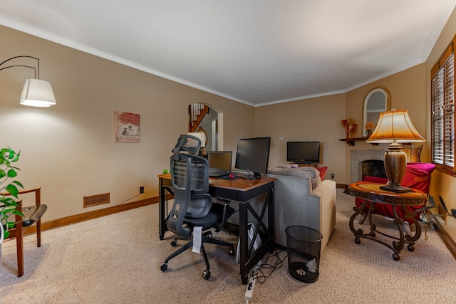 carpeted home office featuring visible vents, arched walkways, crown molding, baseboards, and a tiled fireplace