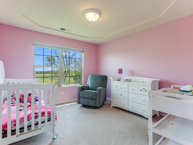 bedroom with carpet, a crib, baseboards, and a tray ceiling
