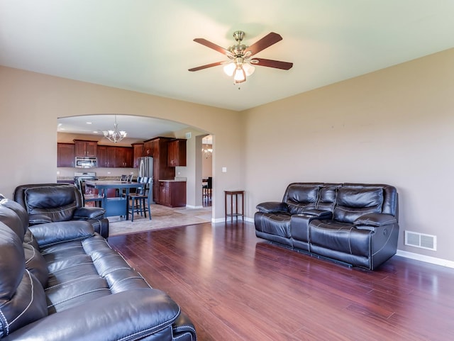 living area with arched walkways, baseboards, light wood-style flooring, a ceiling fan, and a chandelier