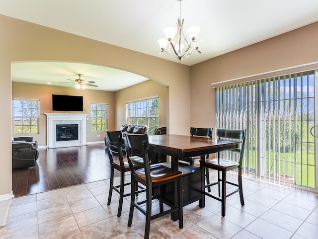 dining room featuring arched walkways, plenty of natural light, a chandelier, and a ceiling fan