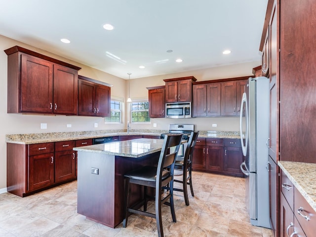kitchen with appliances with stainless steel finishes, a kitchen island, pendant lighting, light stone counters, and a sink