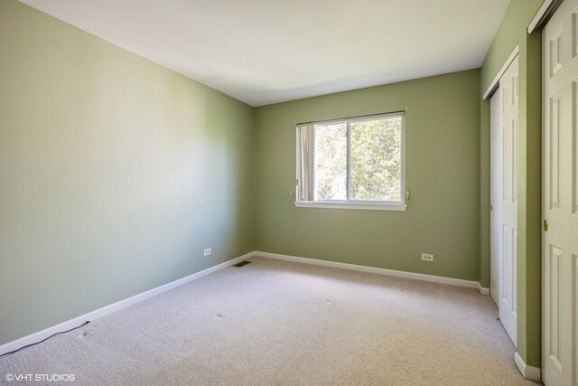 unfurnished bedroom with light carpet, baseboards, and a closet