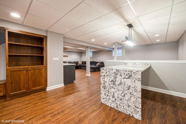 bar with dark wood-type flooring, baseboards, hanging light fixtures, a drop ceiling, and recessed lighting