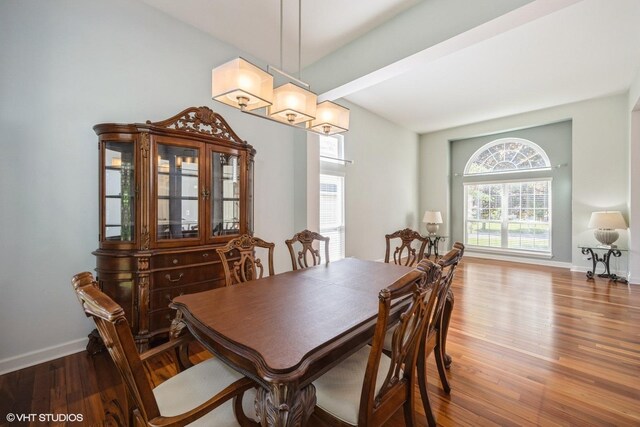 dining area with wood finished floors, baseboards, and beamed ceiling
