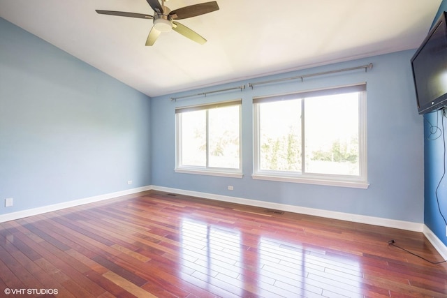 spare room with dark wood finished floors, lofted ceiling, a ceiling fan, and baseboards