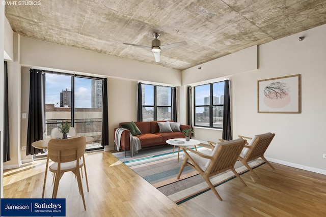 living room with a wealth of natural light, wood finished floors, baseboards, and ceiling fan
