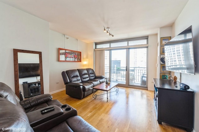living room featuring expansive windows, baseboards, and light wood finished floors