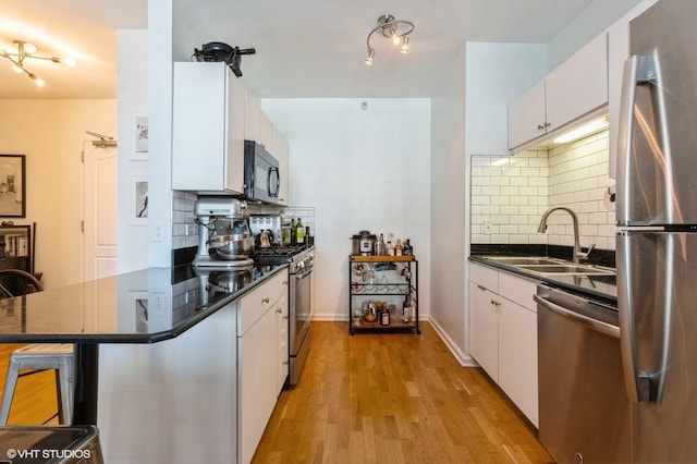 kitchen featuring stainless steel appliances, a sink, dark countertops, and tasteful backsplash