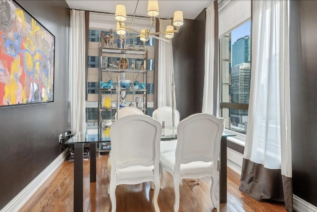 dining space featuring a notable chandelier, baseboards, and wood finished floors