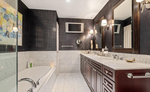 full bathroom featuring a bath, a sink, tile walls, double vanity, and marble finish floor