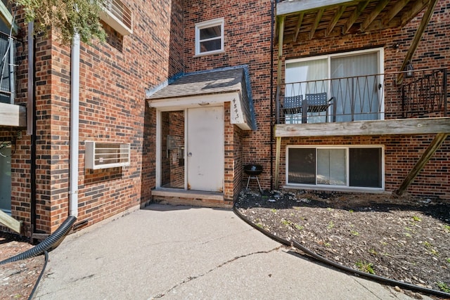 property entrance featuring brick siding and a balcony
