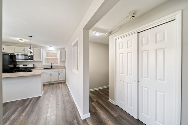 kitchen with a sink, white cabinets, appliances with stainless steel finishes, and dark wood finished floors