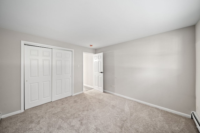 unfurnished bedroom with a baseboard heating unit, a closet, baseboards, and carpet floors