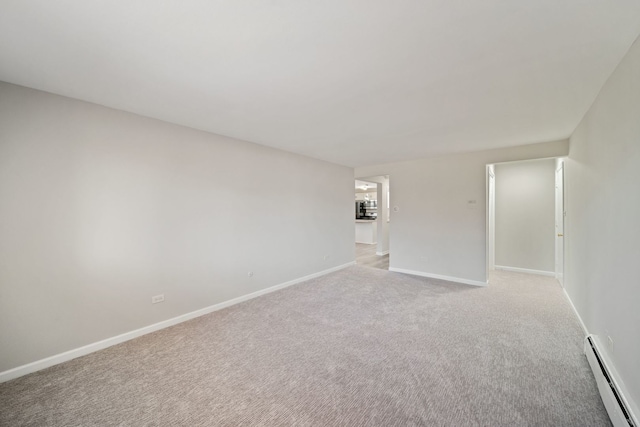 empty room with light colored carpet, a baseboard heating unit, and baseboards