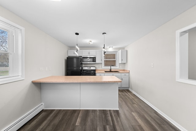 kitchen featuring a baseboard heating unit, a peninsula, black appliances, dark wood finished floors, and a sink