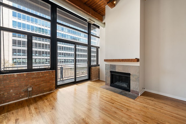 unfurnished living room featuring brick wall, a fireplace, wood ceiling, and wood finished floors
