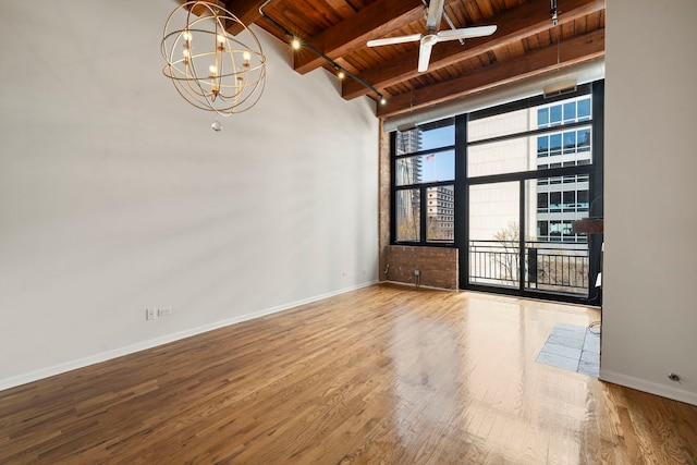 empty room with wood ceiling, baseboards, beam ceiling, and wood finished floors