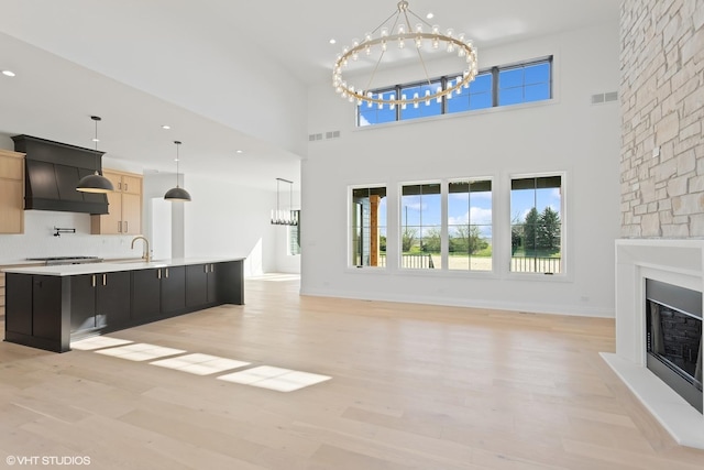 unfurnished living room featuring a large fireplace, visible vents, plenty of natural light, and a notable chandelier