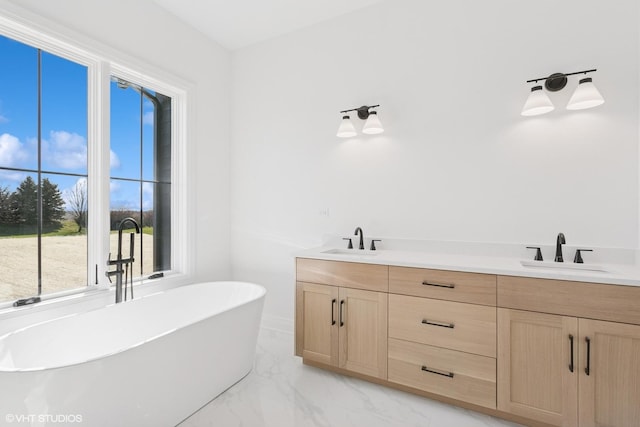 full bathroom featuring a freestanding bath, double vanity, marble finish floor, and a sink
