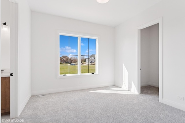unfurnished room with carpet flooring, visible vents, and baseboards