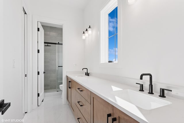 bathroom featuring a shower stall, double vanity, marble finish floor, and a sink