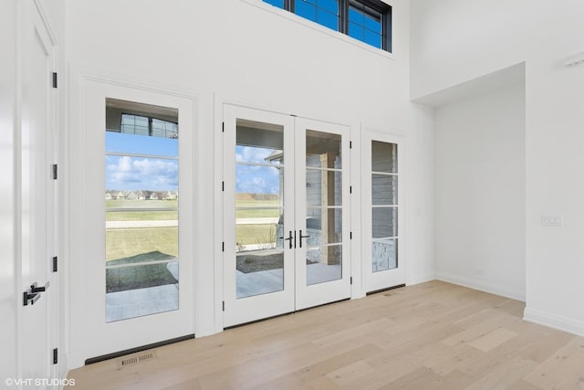 entryway featuring french doors, baseboards, and light wood-style floors