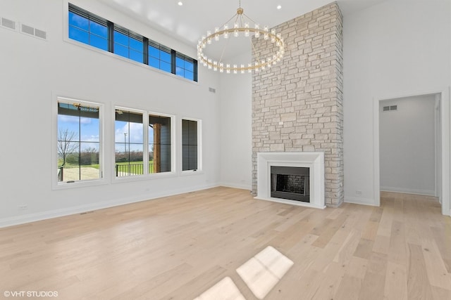 unfurnished living room featuring a chandelier, visible vents, light wood-type flooring, and a high ceiling