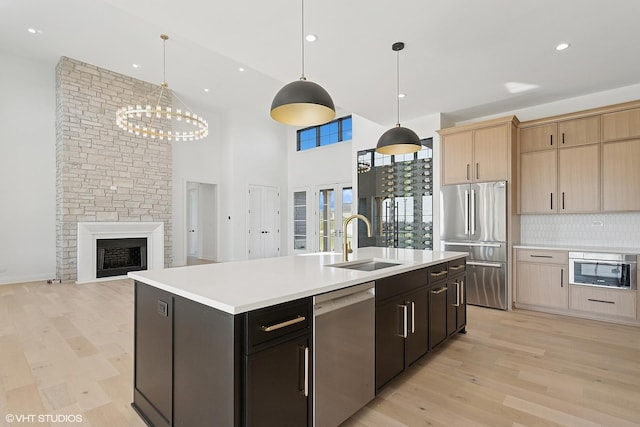 kitchen with tasteful backsplash, light wood-style flooring, light countertops, stainless steel appliances, and a sink