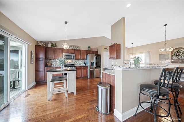 6834 Oak View Ct, Oak Forest, IL 60452 - kitchen featuring stainless steel appliances, lofted ceiling, a kitchen breakfast bar, light wood-style flooring, and backsplash
