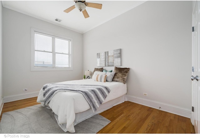 bedroom featuring baseboards, wood finished floors, ceiling fan, and ornamental molding