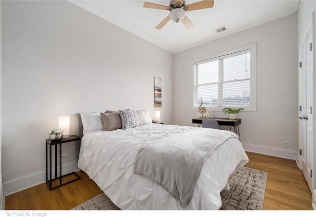 bedroom with light wood-style floors, baseboards, ornamental molding, and a ceiling fan