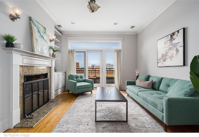 living room with crown molding, light wood-type flooring, and a high end fireplace