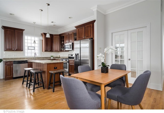 dining room with light wood-type flooring and ornamental molding