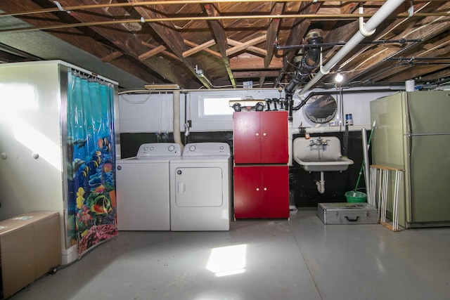 basement featuring freestanding refrigerator, washer and dryer, and a sink