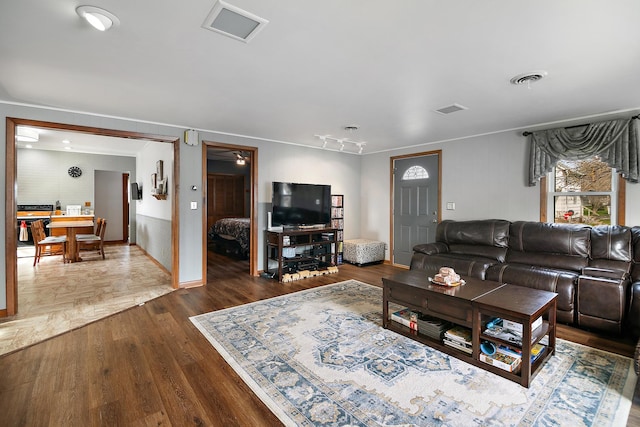 living room featuring baseboards, ornamental molding, dark wood-type flooring, and visible vents
