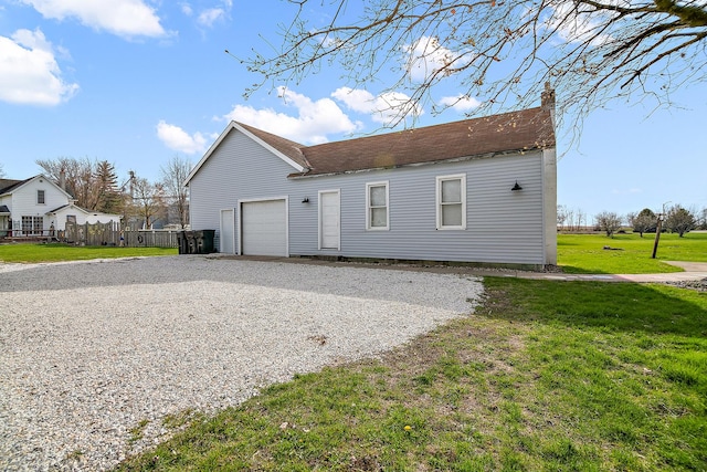 exterior space with gravel driveway, fence, an attached garage, a lawn, and roof with shingles