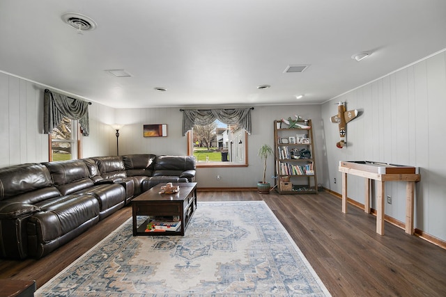 living area with crown molding, wood finished floors, and visible vents