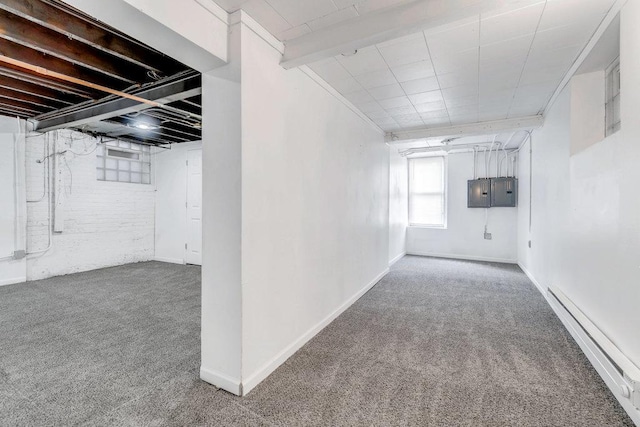 below grade area with electric panel, baseboards, carpet, and a baseboard radiator