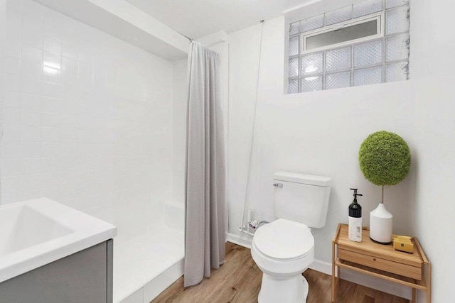 bathroom with baseboards, wood finished floors, toilet, and curtained shower