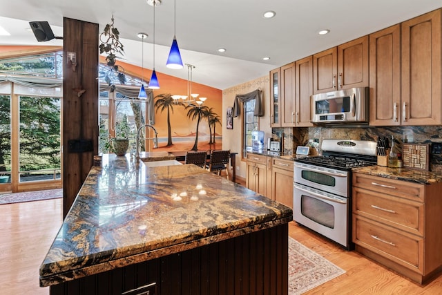 kitchen featuring a notable chandelier, a sink, appliances with stainless steel finishes, light wood finished floors, and decorative backsplash