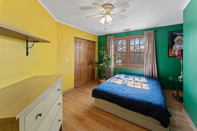 bedroom featuring visible vents, baseboards, ornamental molding, ceiling fan, and light wood-style flooring