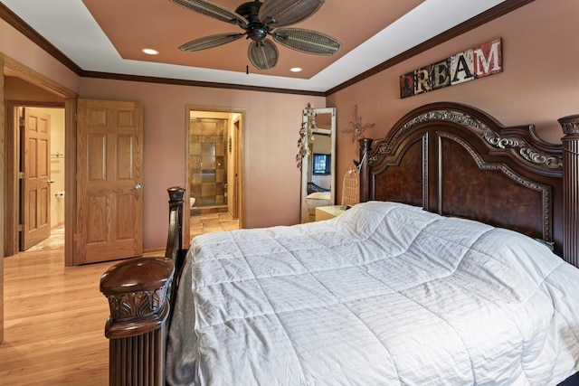 bedroom with recessed lighting, a tray ceiling, ornamental molding, and connected bathroom