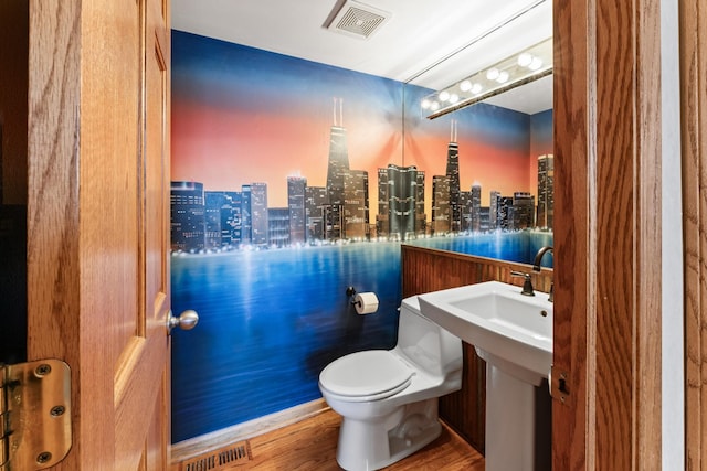 bathroom with toilet, a city view, wood finished floors, and visible vents