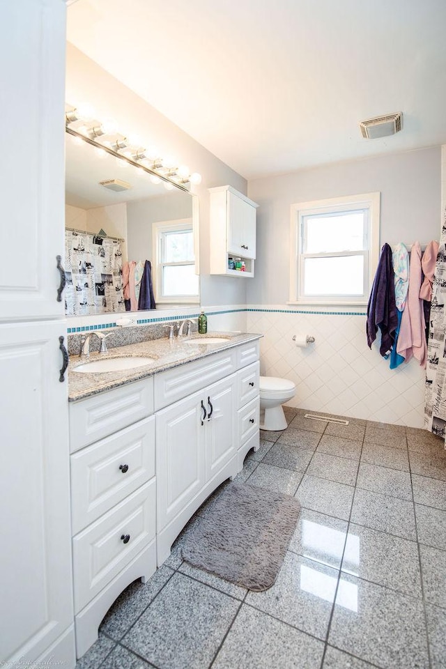 536 Evergreen Ln, Bradley, IL 60915 - full bath with a wainscoted wall, toilet, visible vents, tile walls, and a sink