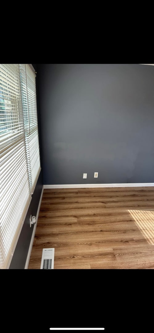 unfurnished room with baseboards, visible vents, and wood finished floors
