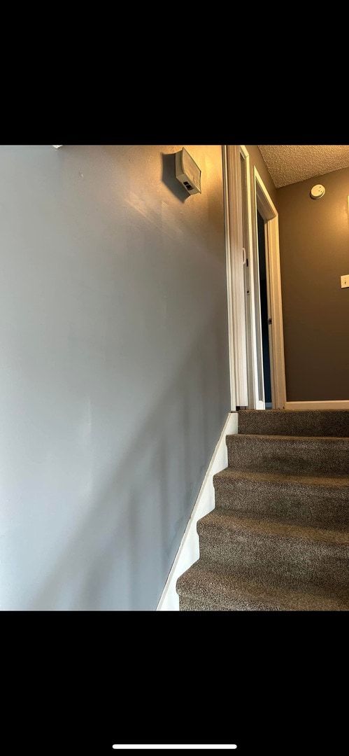staircase featuring a textured ceiling
