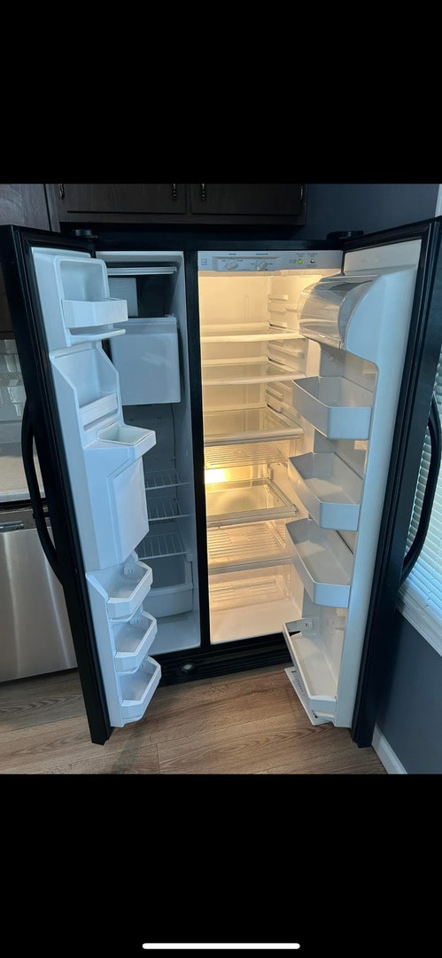 interior details with dark cabinets, wood finished floors, and fridge