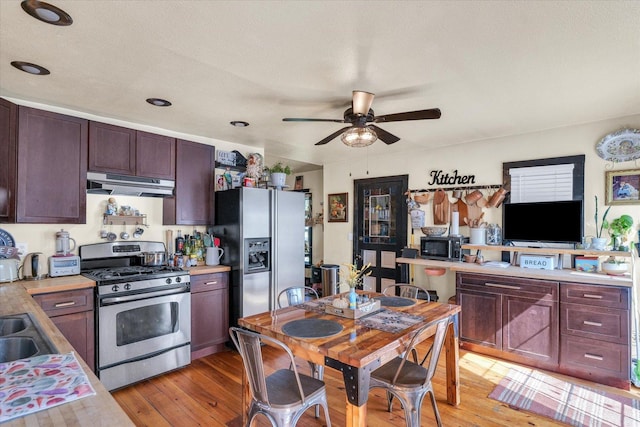 kitchen featuring light wood-style flooring, stainless steel appliances, under cabinet range hood, ceiling fan, and light countertops