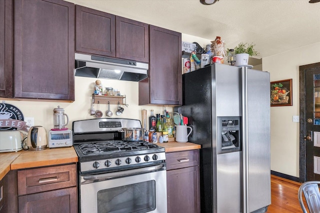 kitchen with light wood-style flooring, stainless steel appliances, dark brown cabinetry, butcher block countertops, and under cabinet range hood